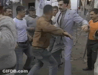 A Man In A Suit Is Standing In A Crowd Of People GIF