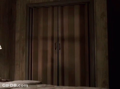 A Man In A Suit Is Standing In A Doorway GIF