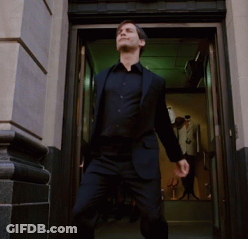 A Man In A Suit Is Standing In A Doorway With His Arms Outstretched GIF