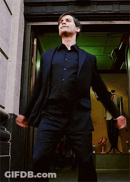 A Man In A Suit Is Standing In A Doorway With His Arms Outstretched GIF