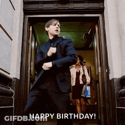 A Man In A Suit Is Standing In A Doorway With His Hands In His Pockets . GIF