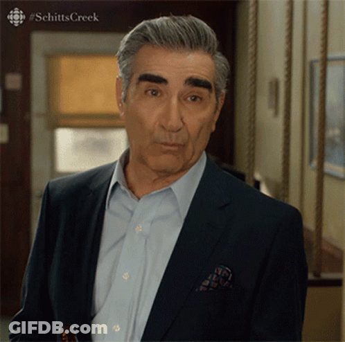 A Man In A Suit Is Standing In A Hallway With #Schitts Creek Written On The Bottom GIF