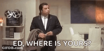 A Man In A Suit Is Standing In A Living Room Holding A Jacket And Talking To Someone . GIF