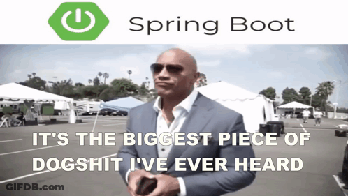 A Man In A Suit Is Standing In A Parking Lot With A Spring Boot Logo Behind Him GIF