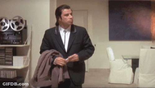 A Man In A Suit Is Standing In A Room GIF