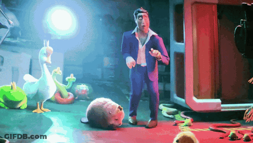 A Man In A Suit Is Standing In A Room Surrounded By Stuffed Animals Including A Duck And A Snake GIF