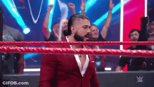 A Man In A Suit Is Standing In A Wrestling Ring . GIF