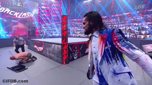 A Man In A Suit Is Standing In A Wrestling Ring With A Referee . GIF