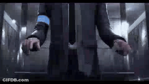 A Man In A Suit Is Standing In An Elevator With His Hands On The Buttons . GIF