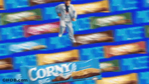 A Man In A Suit Is Standing In Front Of A Box Of Corny Big GIF