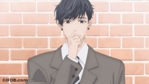 A Man In A Suit Is Standing In Front Of A Brick Wall With His Hand On His Chin GIF