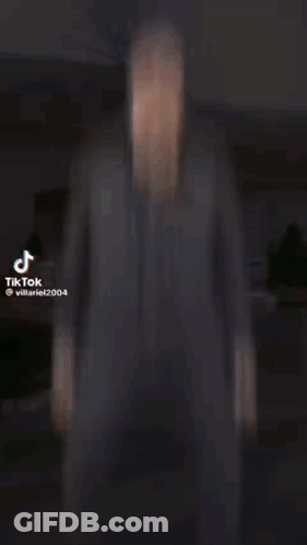 A Man In A Suit Is Standing In Front Of A Building In A Video . GIF