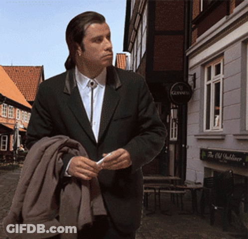 A Man In A Suit Is Standing In Front Of A Building With A Sign That Says Guinness GIF