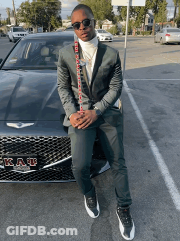 A Man In A Suit Is Standing In Front Of A Car That Says Kappa Alpha GIF