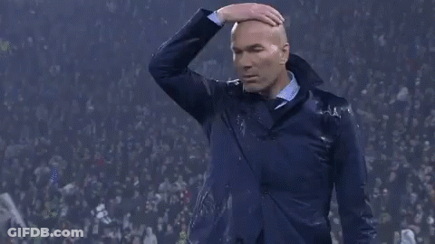A Man In A Suit Is Standing In Front Of A Crowd And Covering His Nose With His Hand . GIF