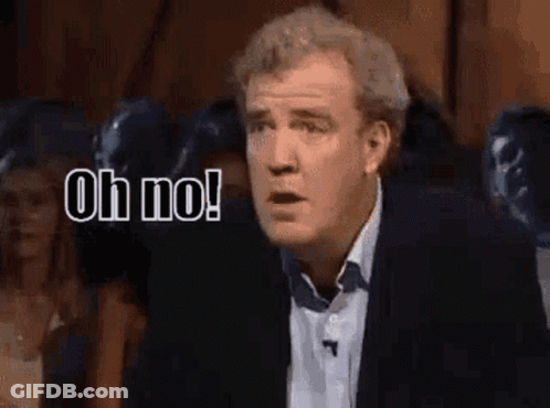 A Man In A Suit Is Standing In Front Of A Crowd And Says Oh No . GIF