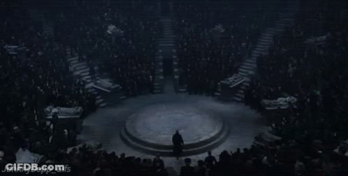 A Man In A Suit Is Standing In Front Of A Crowd Of People . GIF