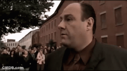 A Man In A Suit Is Standing In Front Of A Crowd Of People . GIF