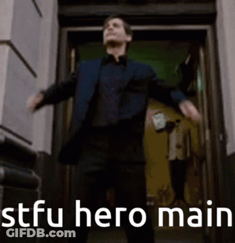 A Man In A Suit Is Standing In Front Of A Door With His Arms Outstretched And The Words Stfu Hero Main Behind Him GIF