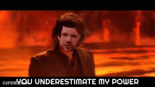 A Man In A Suit Is Standing In Front Of A Fire With The Words `` You Underestimate My Power '' Written Above Him . GIF