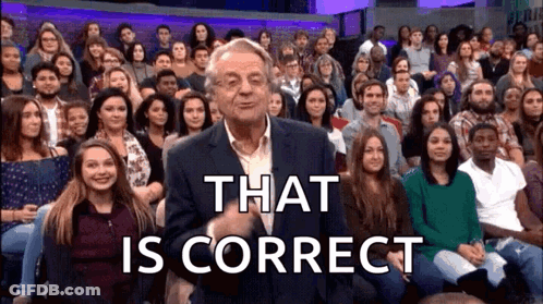 A Man In A Suit Is Standing In Front Of A Large Crowd Of People And Says That Is Correct . GIF