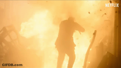 A Man In A Suit Is Standing In Front Of A Large Explosion With Netflix Written On The Bottom GIF