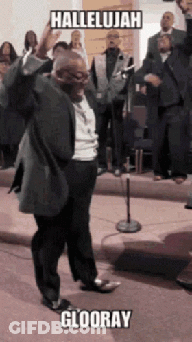 A Man In A Suit Is Standing In Front Of A Microphone With The Words Hallelujah Glooray Written Above Him GIF