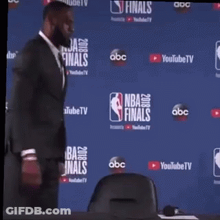 A Man In A Suit Is Standing In Front Of A Nba Finals Backdrop . GIF