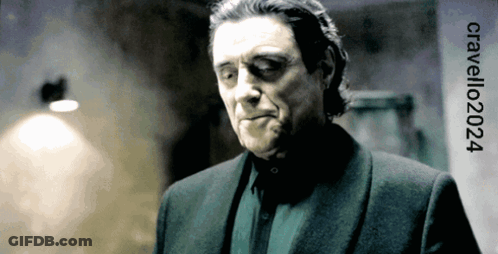 A Man In A Suit Is Standing In Front Of A Sign That Says Cavelli202024 GIF