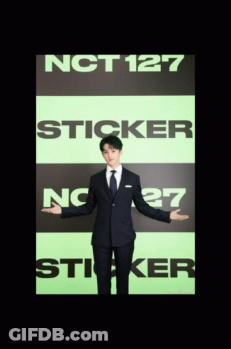 A Man In A Suit Is Standing In Front Of A Sign That Says Nct127 Sticker GIF