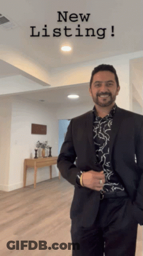 A Man In A Suit Is Standing In Front Of A Sign That Says " New Listing " GIF