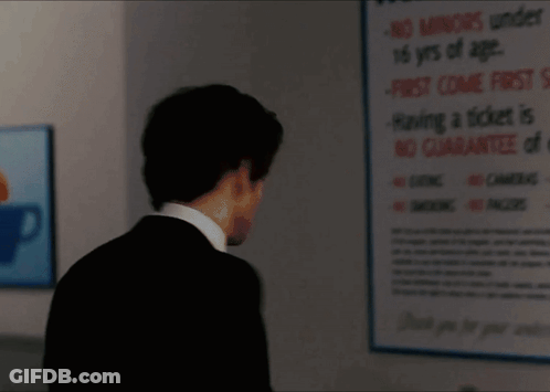 A Man In A Suit Is Standing In Front Of A Sign That Says " No Smoking " GIF