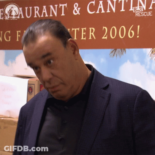 Man In Suit In Front Of Restaurant & Cantina Bar Rescue Sign GIF