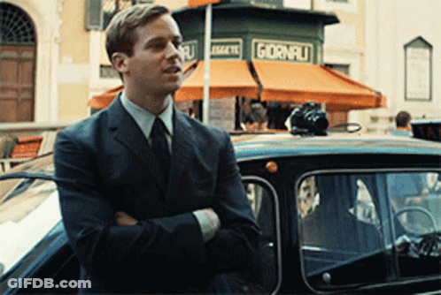 A Man In A Suit Is Standing In Front Of A Store That Says Giorni GIF