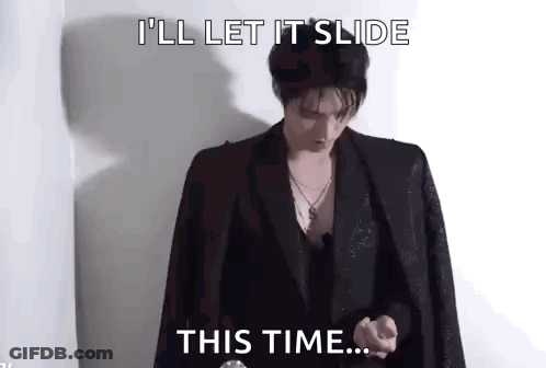 A Man In A Suit Is Standing In Front Of A Wall And Saying `` I 'Ll Let It Slide This Time ... '' . GIF