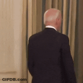 A Man In A Suit Is Standing In Front Of A Wall GIF