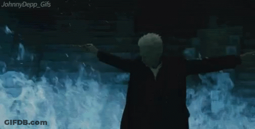 A Man In A Suit Is Standing In Front Of A Wall Of Flames . GIF