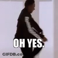A Man In A Suit Is Standing In Front Of A White Wall With The Words Oh Yes Written On It . GIF