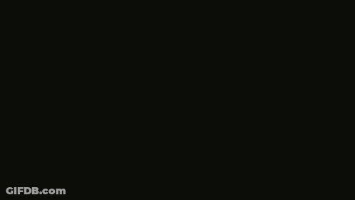 A Man In A Suit Is Standing In The Dark With His Eyes Closed GIF