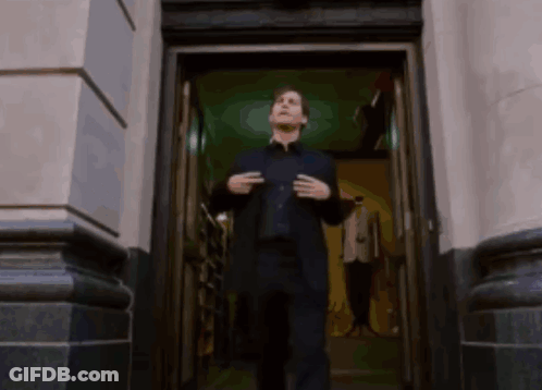 A Man In A Suit Is Standing In The Doorway Of A Building GIF