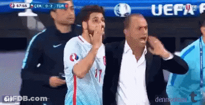 A Man In A Suit Is Standing Next To A Man In A Blue Shirt With The Number 17 On It GIF