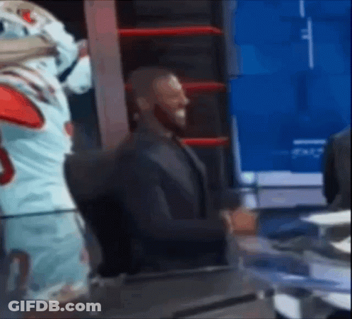A Man In A Suit Is Standing Next To A Mascot In A Boxing Ring . GIF
