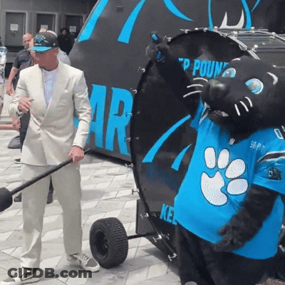 A Man In A Suit Is Standing Next To A Mascot Wearing A Blue Shirt That Says 50 On It GIF