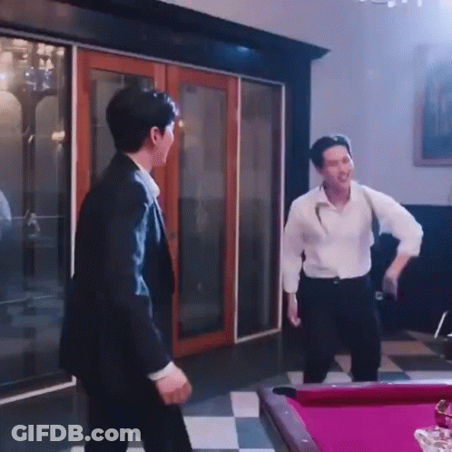 A Man In A Suit Is Standing Next To A Pool Table . GIF