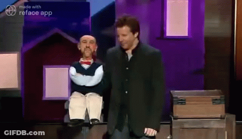 A Man In A Suit Is Standing Next To A Puppet . GIF