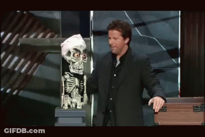 A Man In A Suit Is Standing Next To A Skeleton Puppet GIF