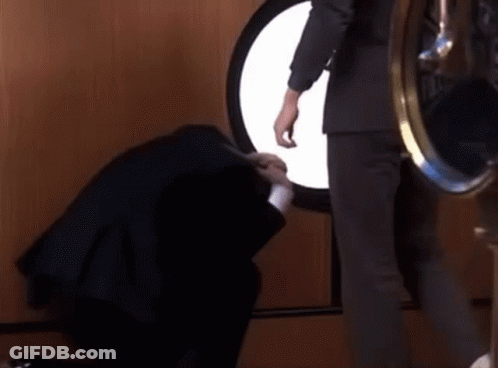 A Man In A Suit Is Standing Next To A Woman In A Black Dress . GIF