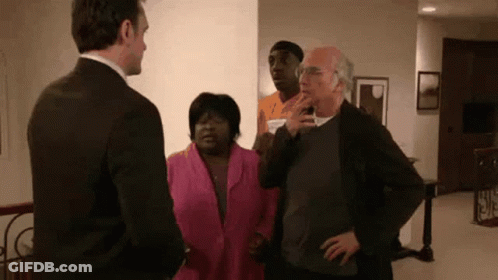 A Man In A Suit Is Standing Next To A Woman In A Pink Jacket . GIF