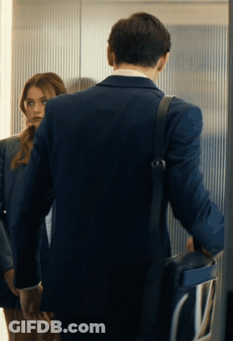 A Man In A Suit Is Standing Next To A Woman In A Suit GIF