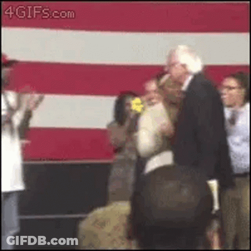 A Man In A Suit Is Standing Next To A Woman In Front Of A Red And White Striped Wall . GIF